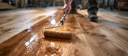 Handwerker trägt Holzbodenöl mit Pinsel auf rohes Holz auf